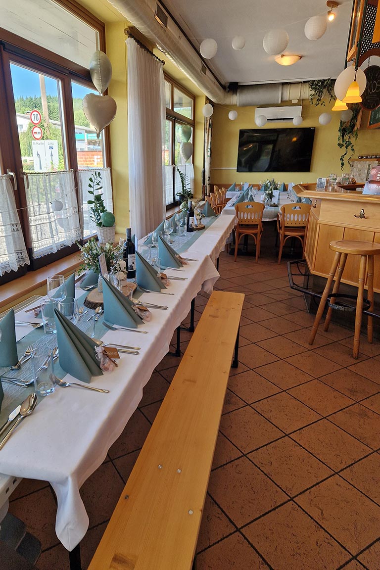 Liebevoll gedeckter Festsaal bei FEIEREI, einladende wedding location in Oberösterreich mit langen Tafeln und moderner Bar für Hochzeitsfeiern.