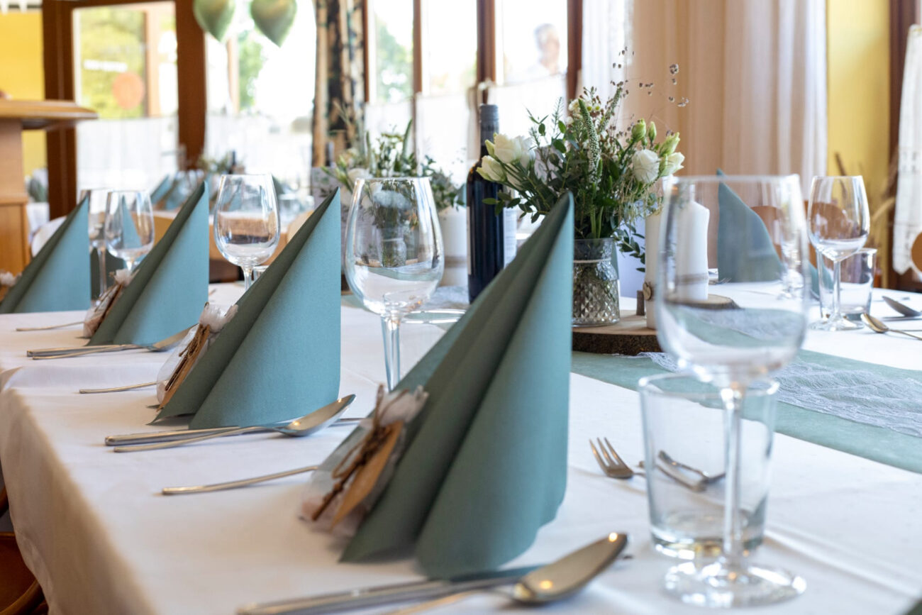 Elegant gedeckter Hochzeitstisch mit grünen Servietten und Blumenschmuck bei FEIEREI, stilvolle wedding location in Oberösterreich.