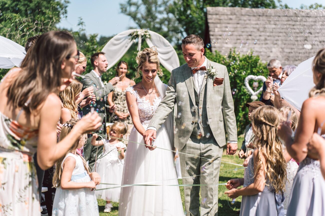 Hochzeitspaar beim Auszug durch die Gäste im Garten der FEIEREI, festliche wedding location in Oberösterreich für unvergessliche Trauungen.